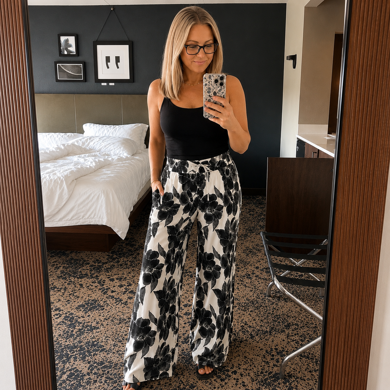Model wearing black and white floral wide-leg pants with a black tank top